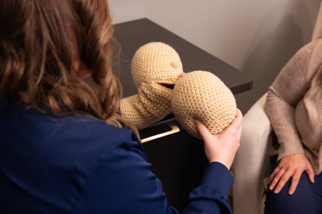 A breastfeeding specialist in Sioux City shows an expecting mother how latching works using puppets at The Sonography Studio.