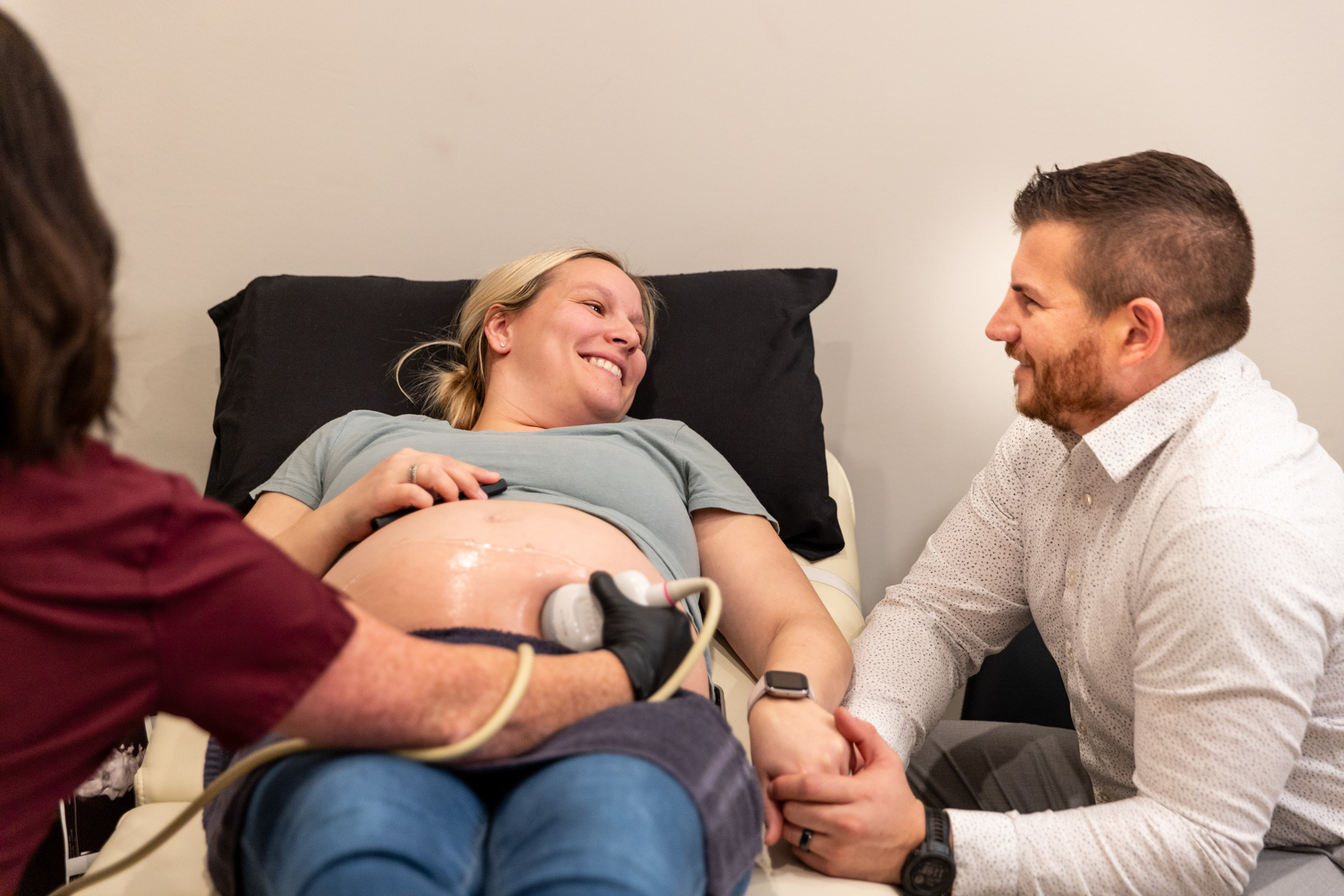 A pregnant woman lying on her back smiles at her husband while receiving an ultrasound at a women's clinic in Sioux City.