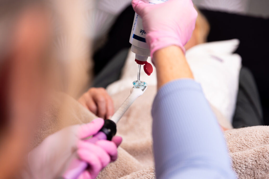 Close up of a gloved medical provider applying lubricant to a handheld device for Vaginal Tightening in Panama City.