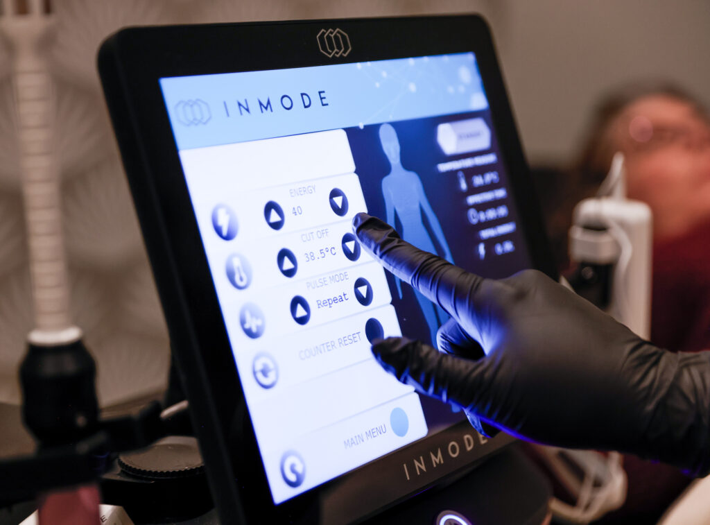 Close up of a hand operating the digital control screen for Vaginal Rejuvenation Near Omaha.