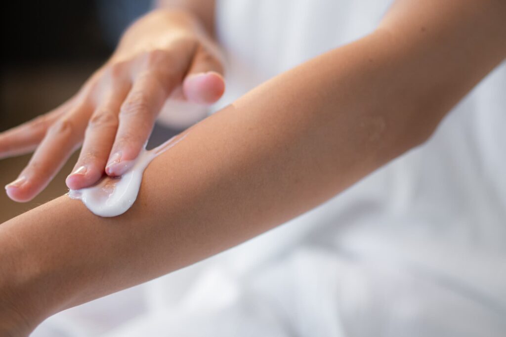Close up of a woman applying cream to her forearm as part of hormone replacement therapy near Storm Lake.